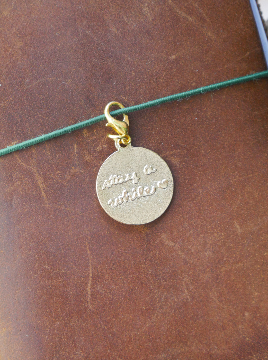 "stay a while" brass charm